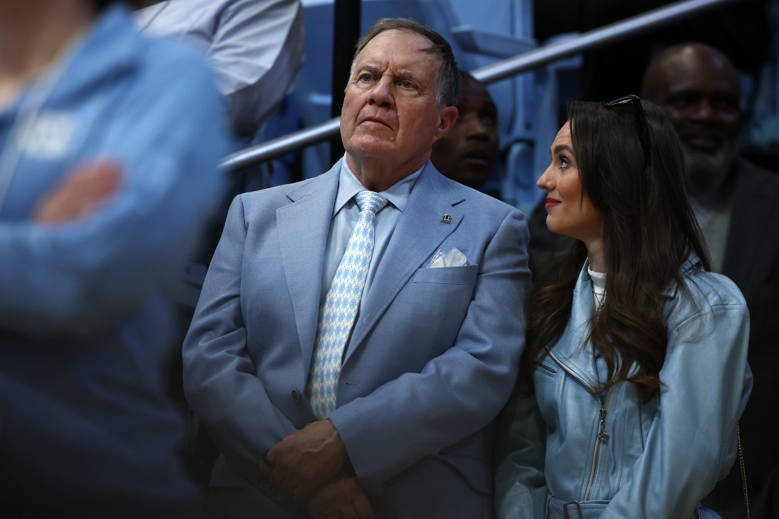 CHAPEL HILL, NORTH CAROLINA - MARCH 08: North Carolina Tar Heels football head coach Bill Belichick and his girlfriend Jordon Hudson look on during the first half of the game between the North Carolina Tar Heels and the Duke Blue Devils at Dean E. Smith Center on March 08, 2025 in Chapel Hill, North Carolina. (Photo by Jared C. Tilton/Getty Images)