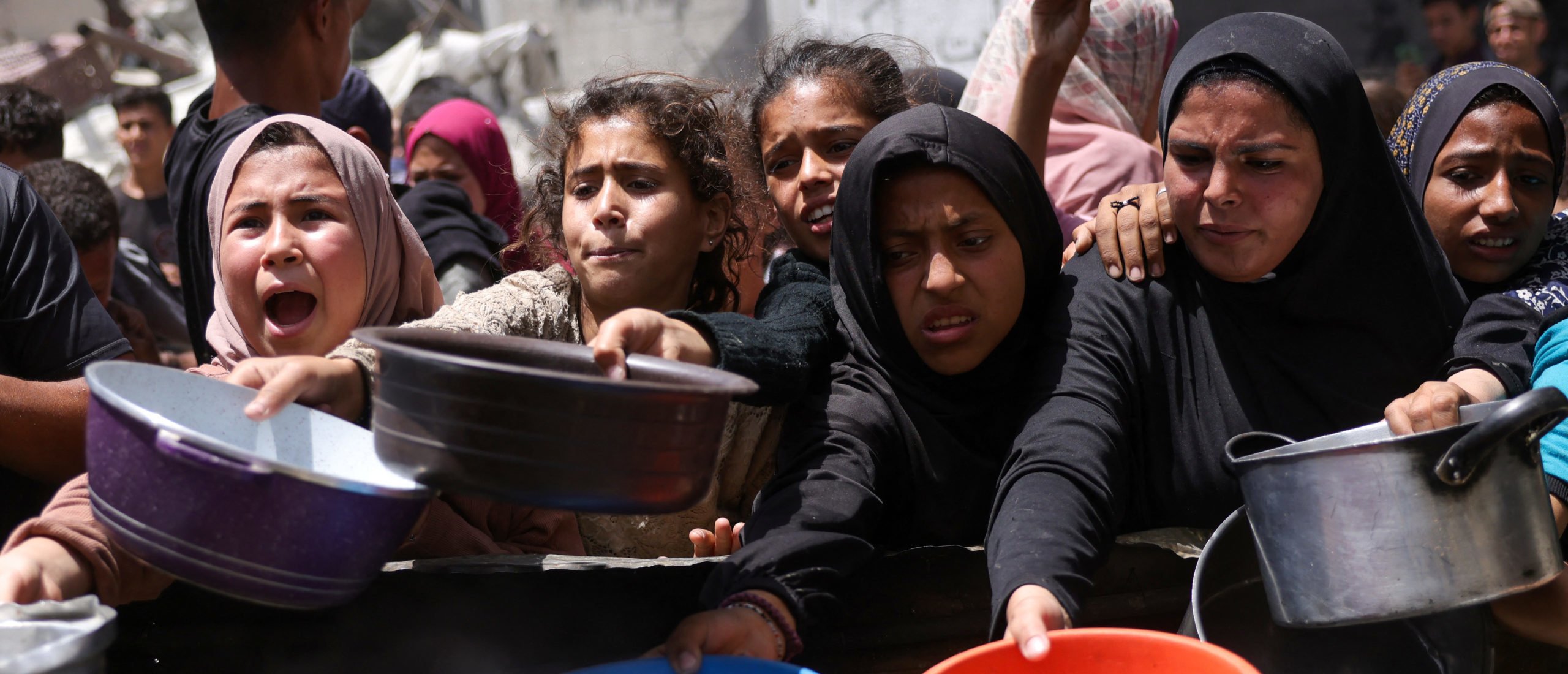 Displaced Palestinians gather to collect portions of cooked food at a charity distribution point in Jabalia in the northern Gaza Strip on May 19, 2025. Prime Minister Benjamin Netanyahu said on May 19 that Israel will