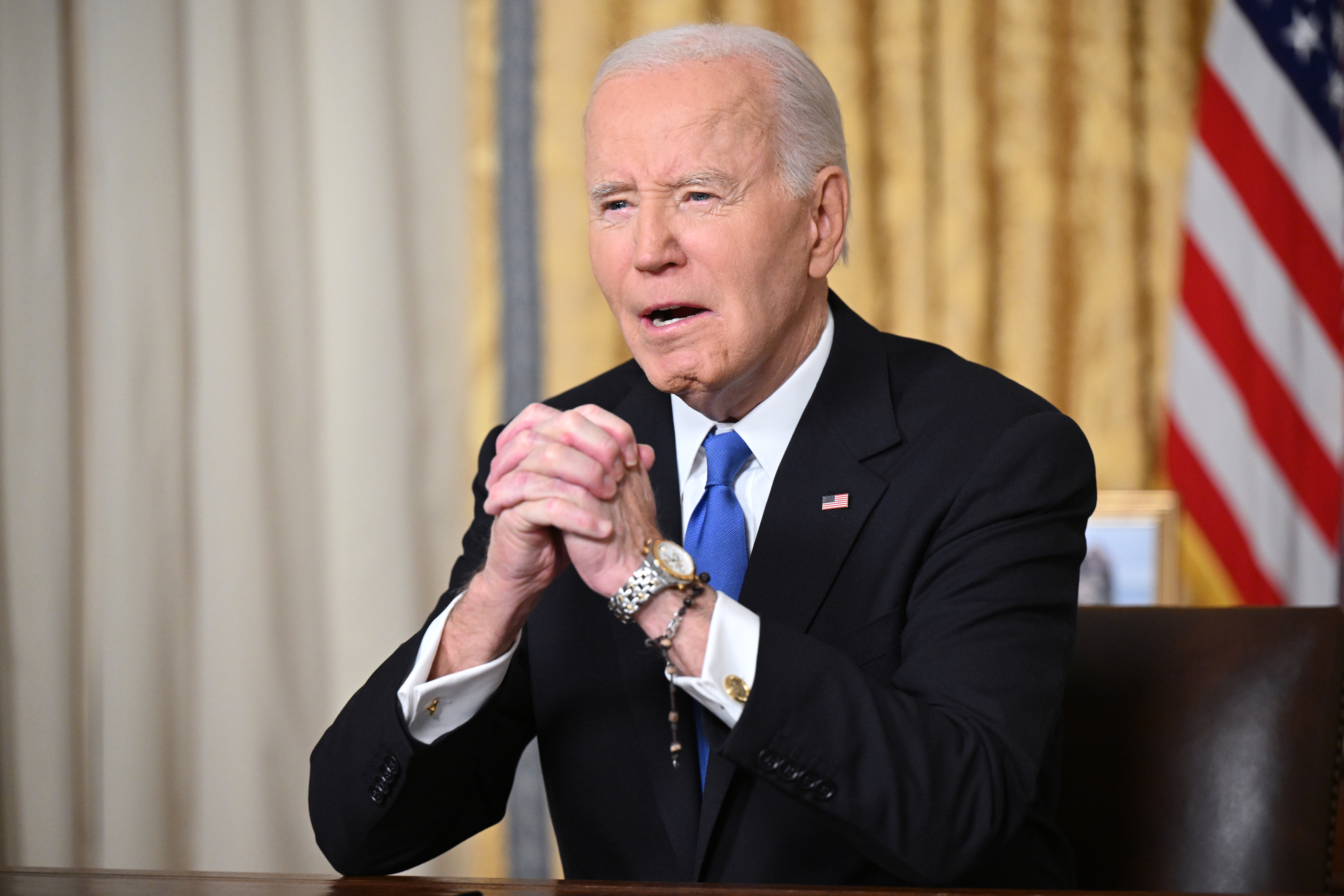 US President Joe Biden clasps his hands as he delivers his farewell address to the nation from the Oval Office of the White House on January 15, 2025 in Washington, DC. (Photo by Mandel Ngan - Pool/Getty Images)