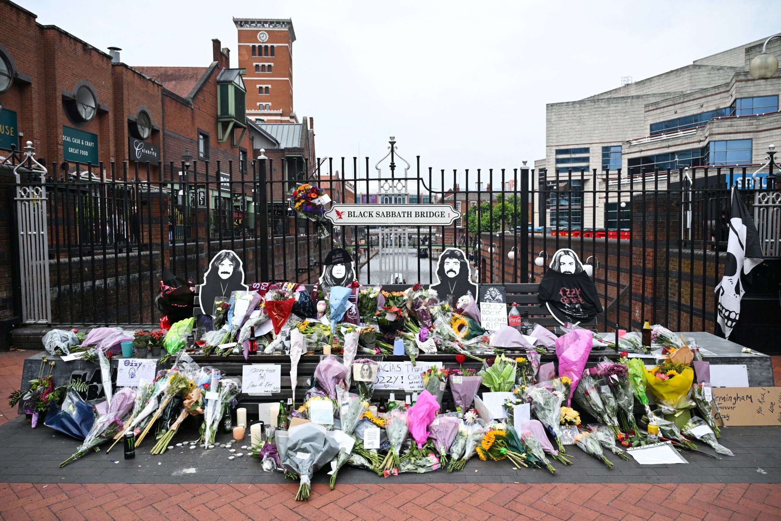 TOPSHOT - A photograph taken on July 23, 2025 shows flowers, candles and drawings left at a makeshift memorial on Black Sabbath Bridge, in tribute of late British singer-songwriter Ozzy Osbourne, in Birmingham, central England, a day after his death. Tributes poured in on July 23, 2025 for hell-raiser singer Ozzy Osbourne as tearful fans laid flowers in his hometown and his Black Sabbath band mates mourned the death of their legendary heavy metal frontman, just weeks after he played an epic farewell concert in their Birmingham hometown. Osbourne, nicknamed the