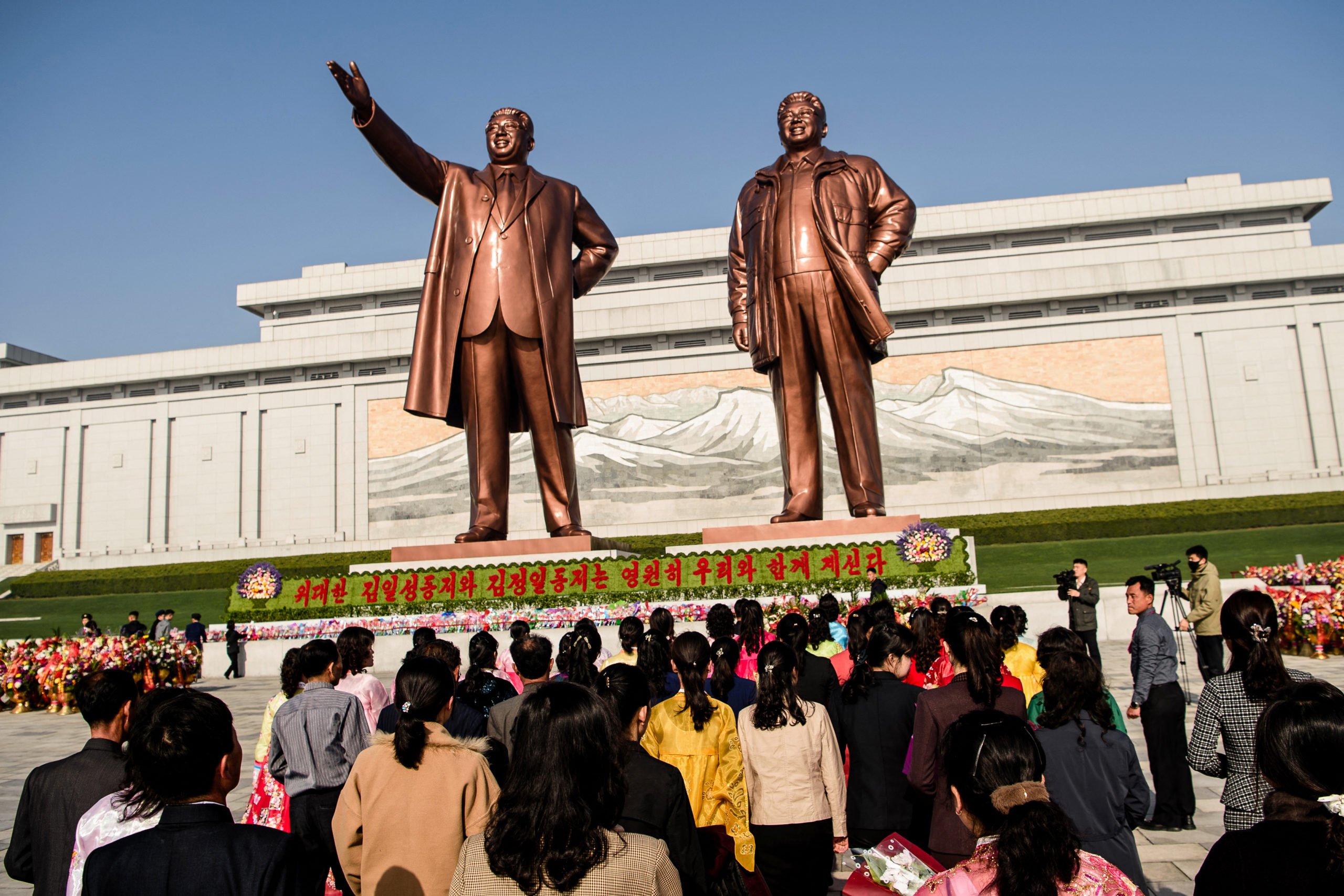 People pay tribute to the statues of late North Korean leaders Kim Il Sung and Kim Jong Il at Mansu Hill in Pyongyang on April 15, 2025, to mark the 113th birth anniversary of late leader Kim Il Sung, celebrated as the 