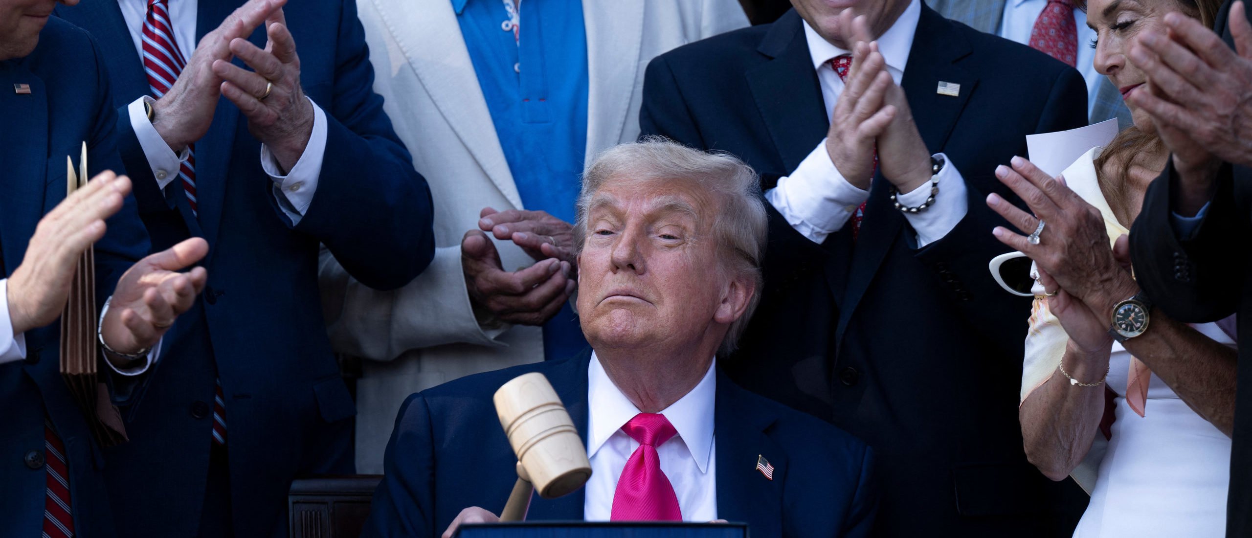 US President Donald Trump (C) holds a gavel after signing the