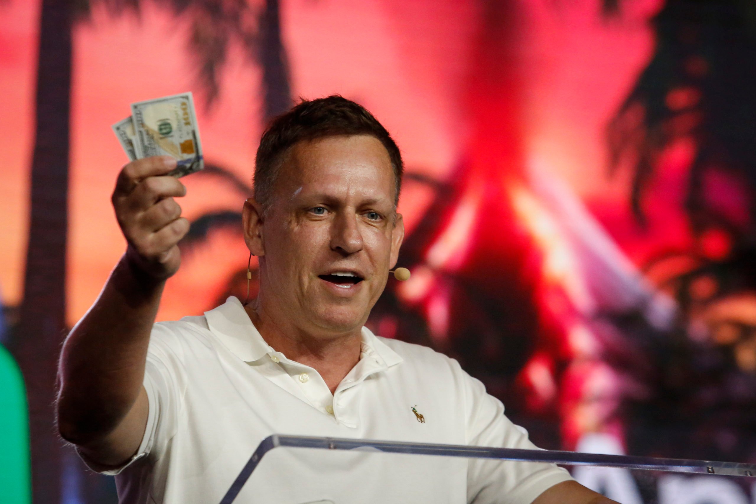 MIAMI, FLORIDA - APRIL 7: Peter Thiel, co-founder of PayPal, Palantir Technologies, and Founders Fund, holds hundred dollar bills as he speaks during the Bitcoin 2022 Conference at Miami Beach Convention Center on April 7, 2022 in Miami, Florida. The worlds largest bitcoin conference runs from April 6-9, expecting over 30,000 people in attendance and over 7 million live stream viewers worldwide. Marco Bello/Getty Images