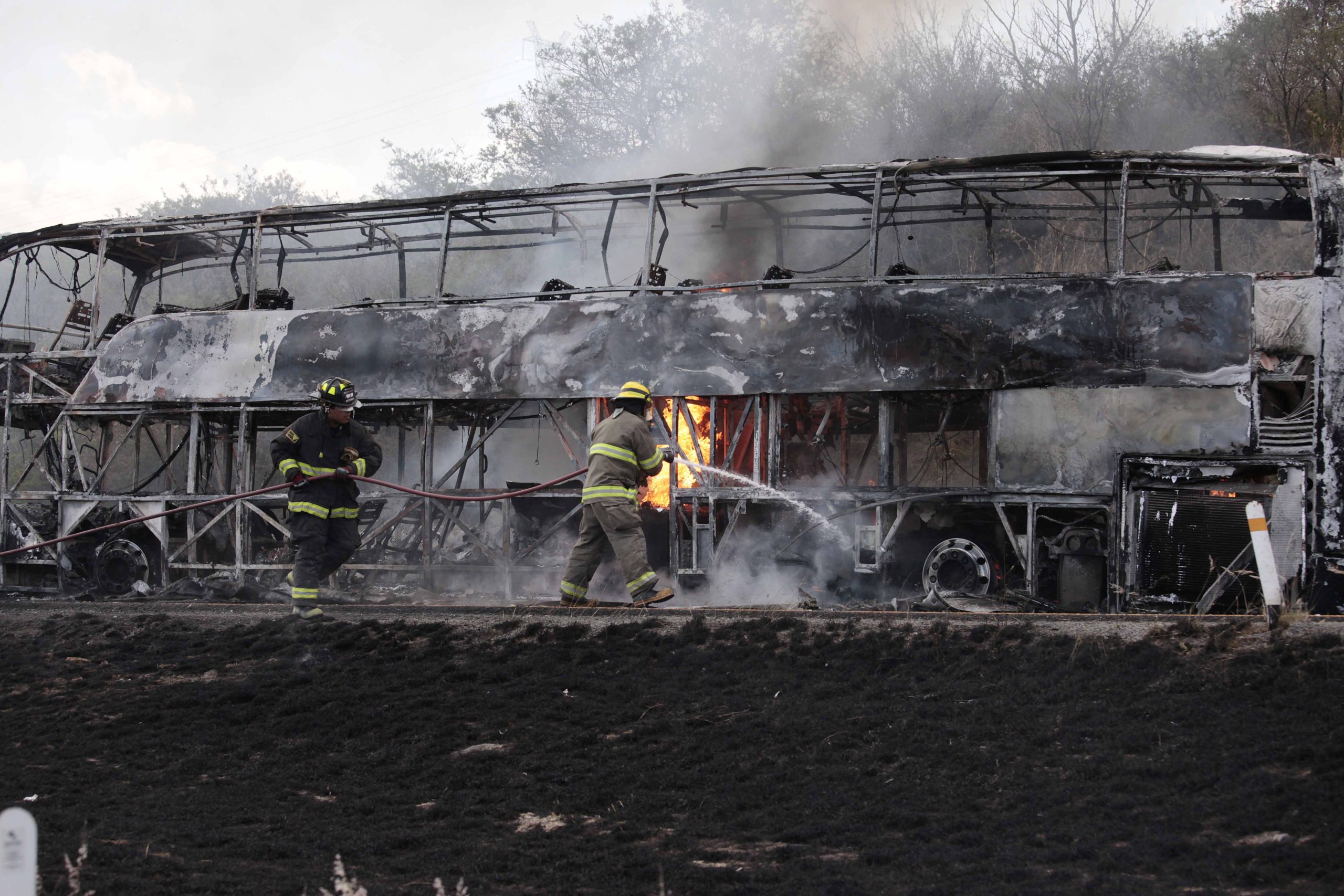 (STR/AFP via Getty Images) Firefighters work on a burned bus in Guadalajara, Mexico, amid an escalation of violence by the Jalisco New Generation Drug Cartel. (STR/AFP via Getty Images)