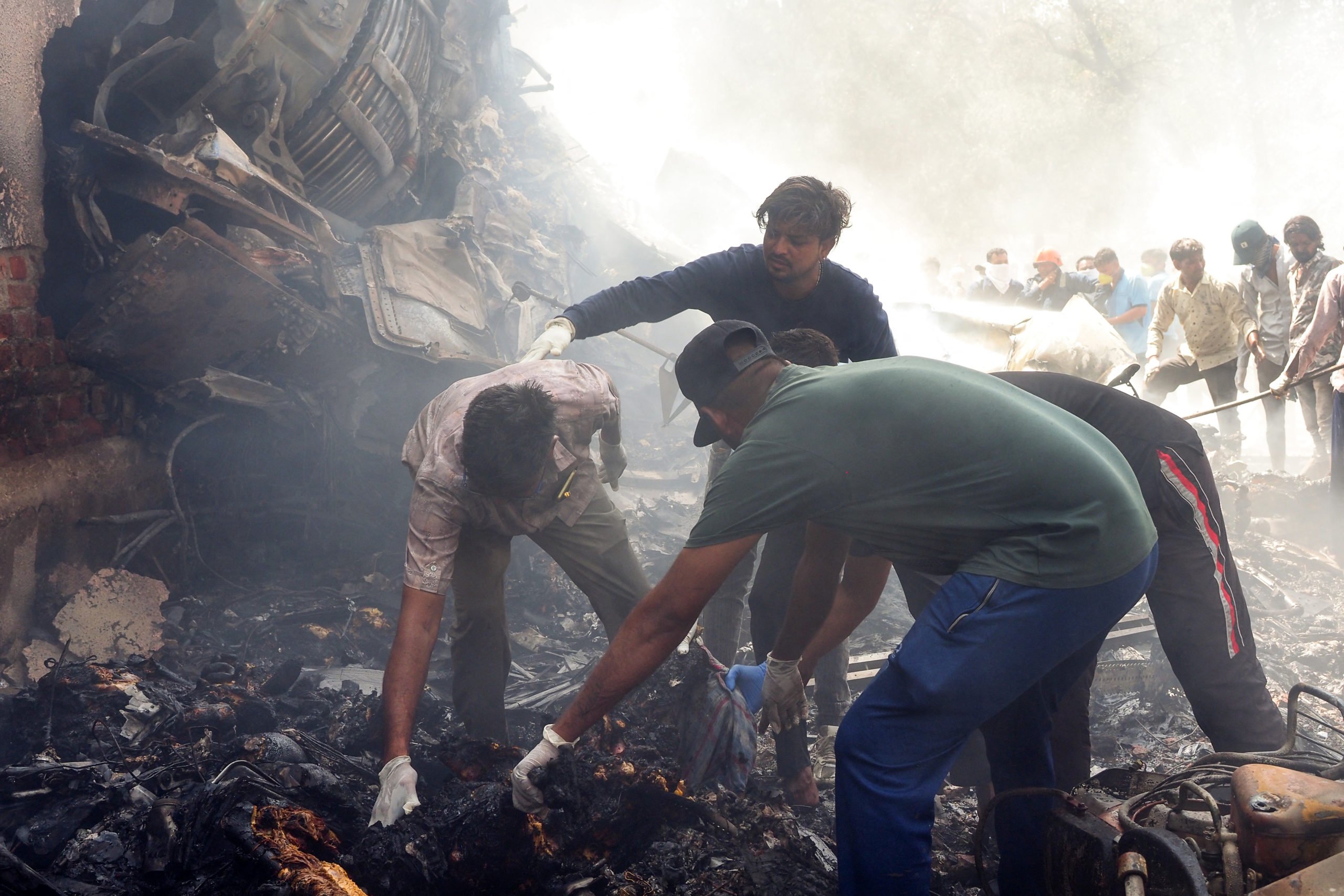 TOPSHOT - Rescue officials work at the site where Air India flight 171 crashed in a residential area near the airport in Ahmedabad on June 12, 2025. The London-bound passenger plane crashed on June 12 in India's western city of Ahmedabad with 242 on board, aviation officials said in what the airline called a "tragic accident".
