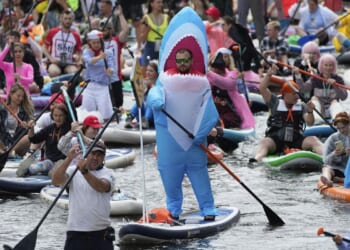 Photos show costumed participants steer stand-up paddle boards at a festival in Russia