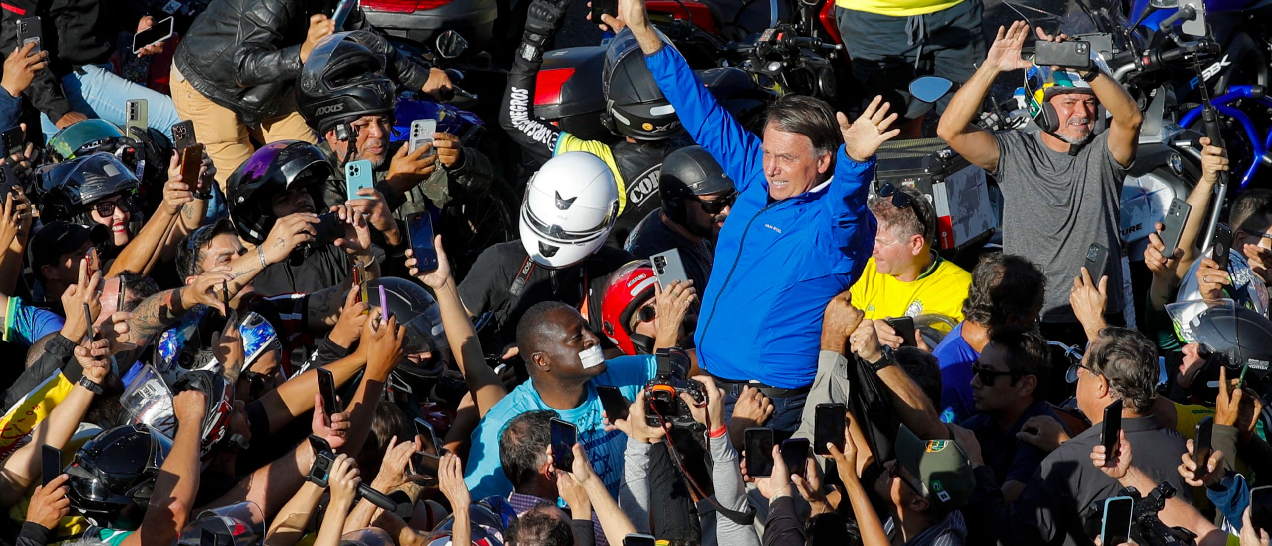 Brazil's former President Jair Bolsonaro (C) greets supporters during a walk to attend a meeting with motorcyclists at Capital Moto Week in Brasilia on July 29, 2025. (Photo by SERGIO LIMA/AFP via Getty Images)