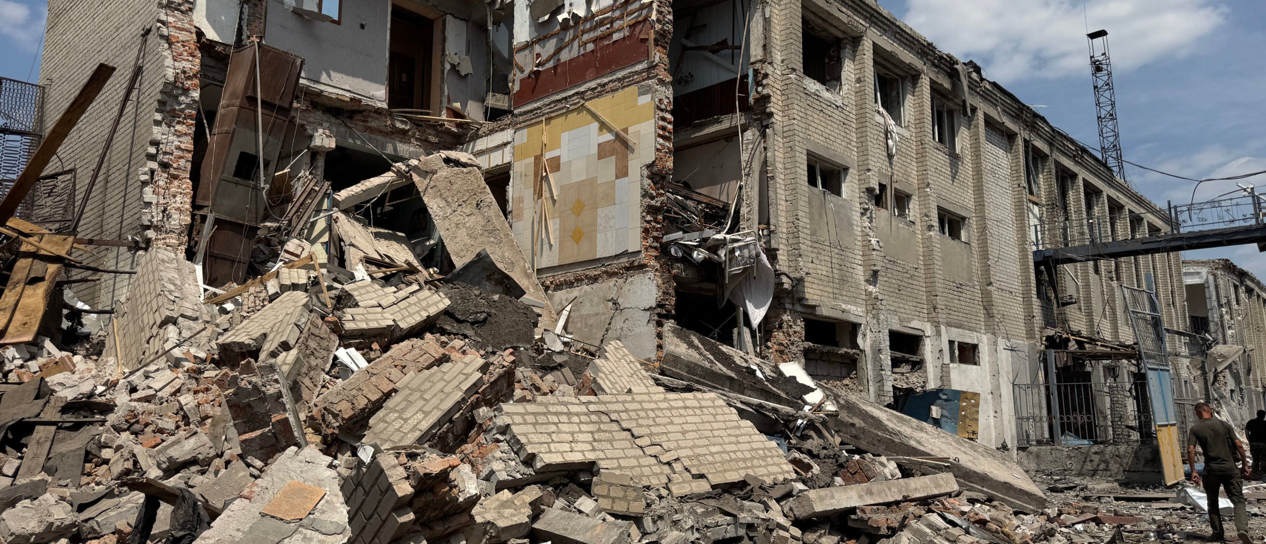 A Ukrainian law enforcement officer walks past a destroyed building of the Bilenkivska correctional colony following an air attack in Bilenke, Zaporizhzhia region on July 29, 2025, amid the Russian invasion of Ukraine. A Russian airstrike on a prison in southeastern Ukraine overnight killed 17 inmates and wounded dozens of others, Kyiv said on July 29, 2025, after Washington pressured Russia to end its invasion. (Photo by OLEXANDR PAVLOV/AFP via Getty Images)