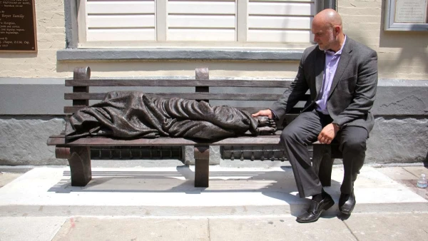 Timothy Schmalz sits beside a bronze casting of his “Homeless Jesus” in Philadelphia, one of more than 50 locations that has installed the work. Credit: Courtesy of Timothy Schmalz