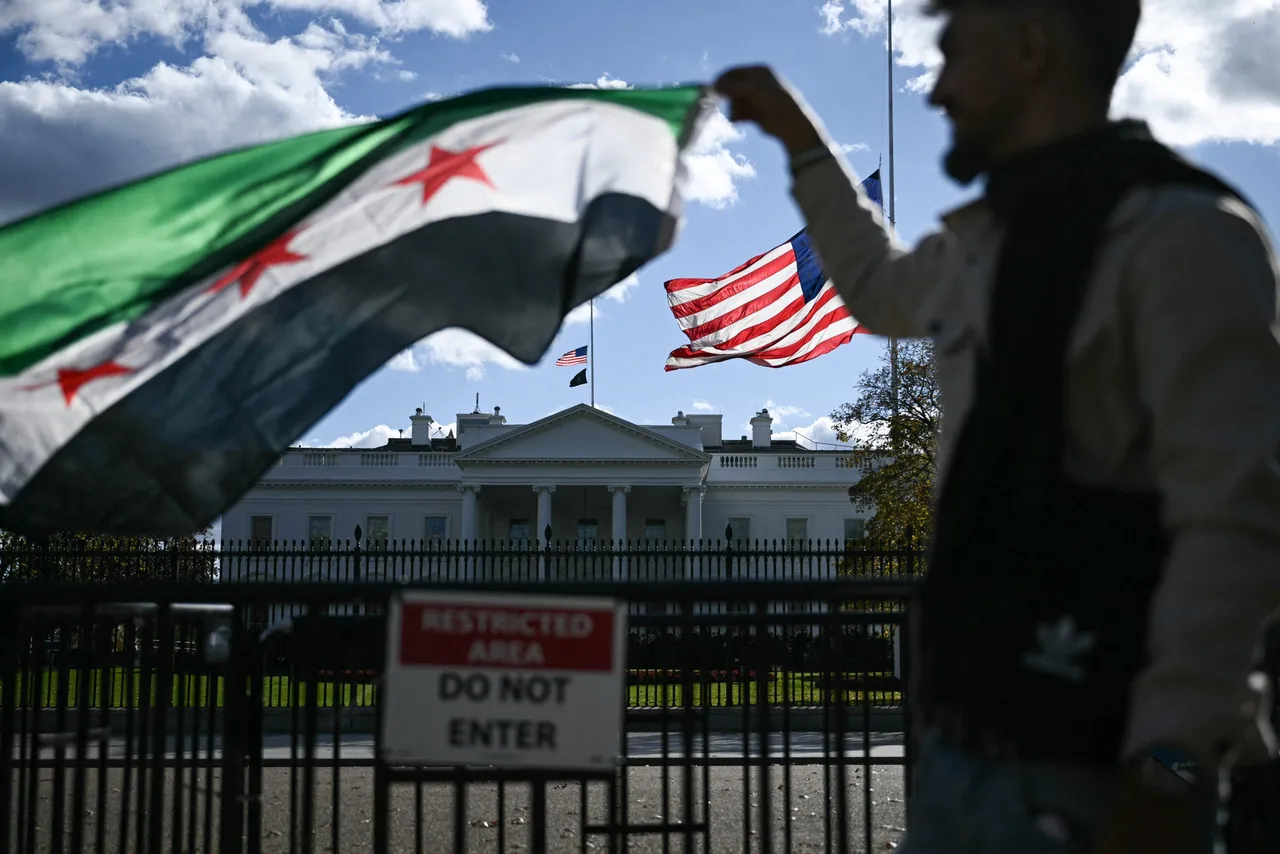 A man holds a Syrian flag across the street from the White House after Syrian President Ahmed al-Sharaa met with US President Donald Trump at White House in Washington, DC on November 10, 2025. Syria's President Ahmed al-Sharaa met US President Donald Trump at the White House on Monday for unprecedented talks, just days after Washington removed him from a terrorism blacklist. Sharaa, whose rebel forces ousted longtime ruler Bashar al-Assad late last year, is the first Syrian leader to visit the White House since the country's 1946 independence. (Photo by BRENDAN SMIALOWSKI/AFP via Getty Images)
