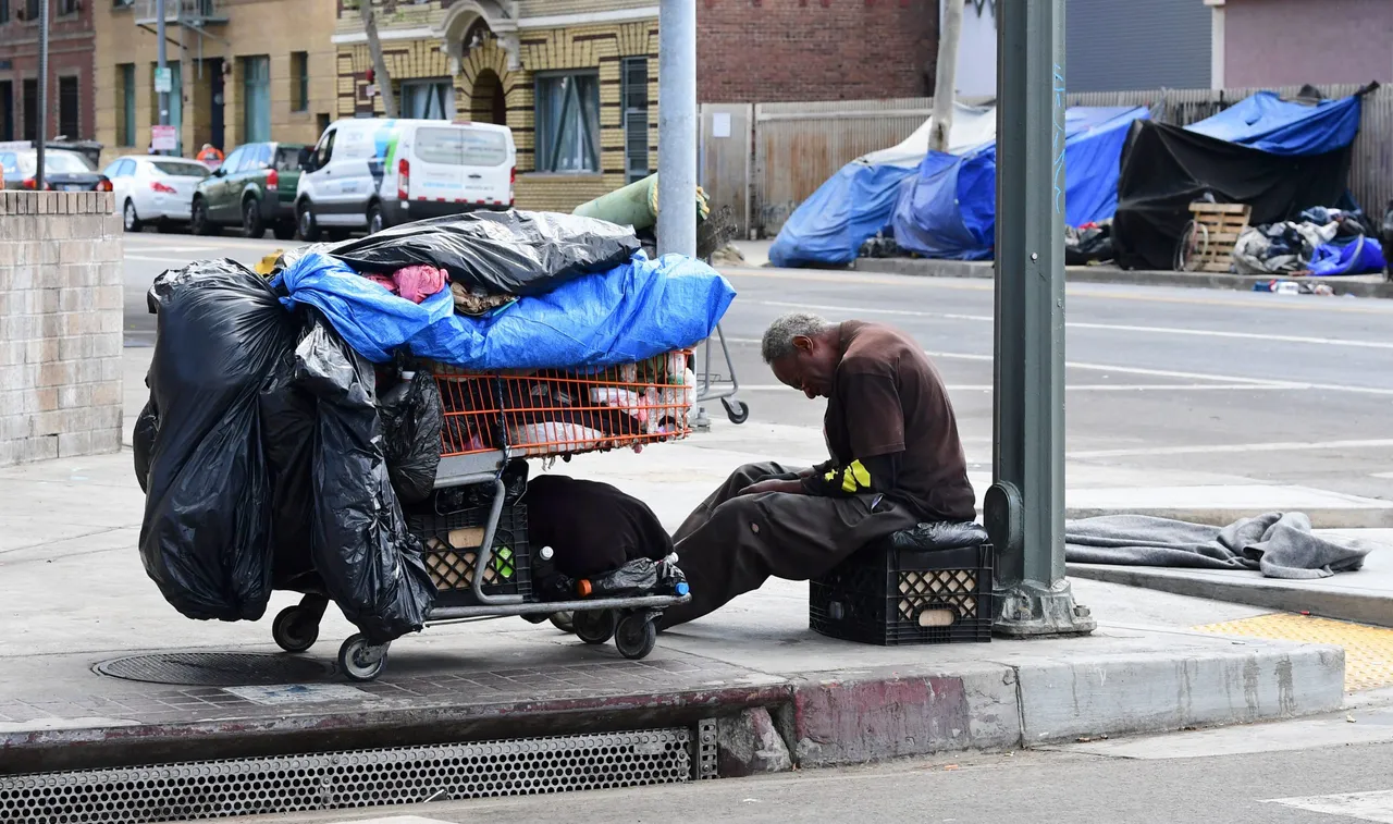 A homeless man sits beside his belongings on the streets in the Skid Row community of Los Angeles, California on April 26, 2021. (Photo by FREDERIC J. BROWN/AFP via Getty Images)