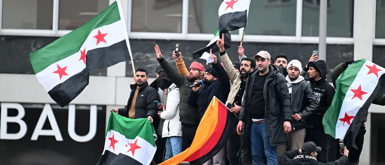 Members of the Syrian community hold flags of Syria and Germany as they rally on December 8, 2024 in Berlin, Germany, to celebrate the downfall of Syrian dictator Bashar al-Assad.