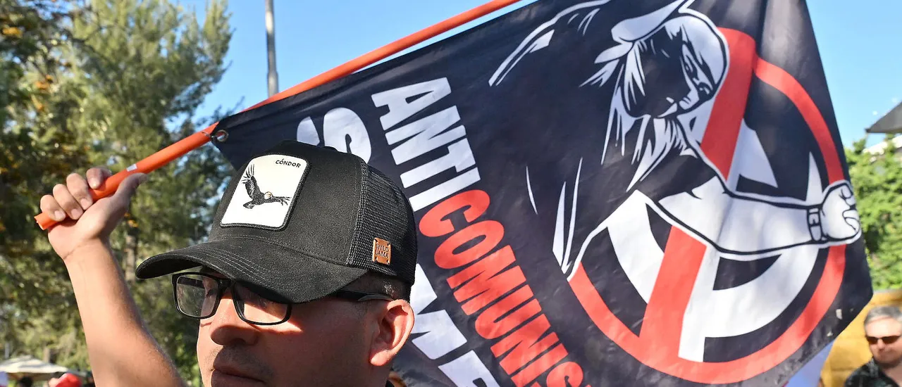 A supporter of Chile's presidential candidate Johannes Kaiser of the Libertarian National Party holds a banner reading Always Anti-Communist during his closing campaign rally in Santiago on November 12, 2025.