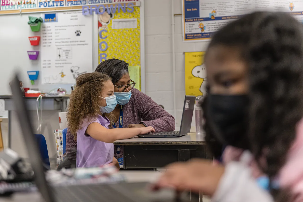 Nicole Brown, a second grade teacher, sits at a laptop computer with one of her students during a lesson at Carter Traditional Elementary School on January 24, 2022 in Louisville, Kentucky.