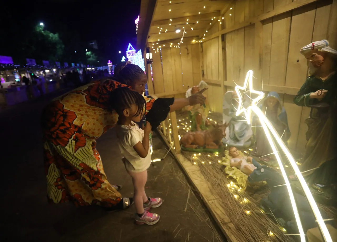 A woman and her daughter visits a decorated Christmas village during a Christmas light fair in Abuja on December 22, 2022. (Photo by KOLA SULAIMON/AFP via Getty Images)