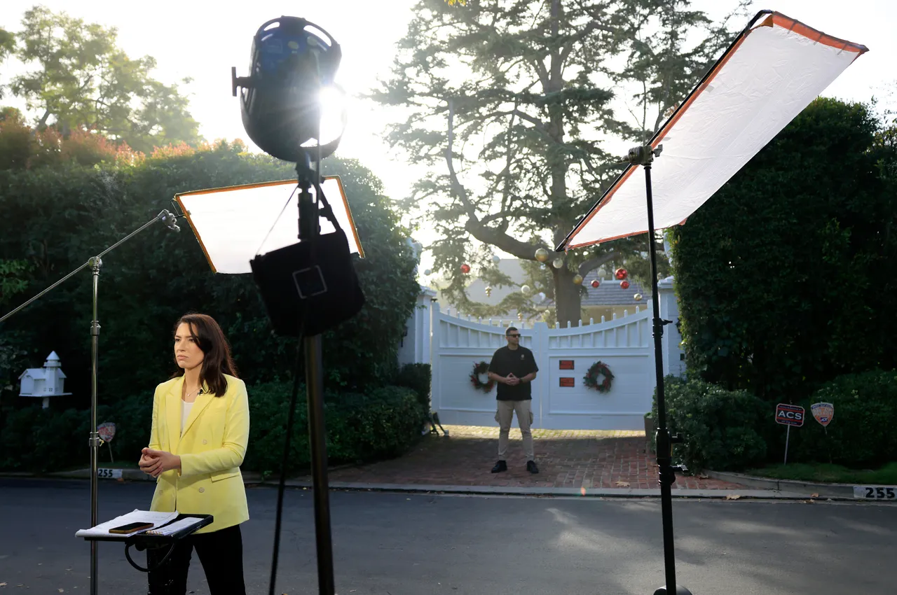 BRENTWOOD, CALIFORNIA - DECEMBER 16: A reporter works in front of director Rob Reiner's home as a security guard keeps watch on December 16, 2025 in Brentwood, California. The LAPD confirmed that Rob Reiner and his wife Michele Singer Reiner were found dead in their Brentwood home. Their son Nick was arrested in connection to their deaths and will be charged with two counts of first-degree murder, according to the Los Angeles County district attorney. (Photo by Mario Tama/Getty Images)