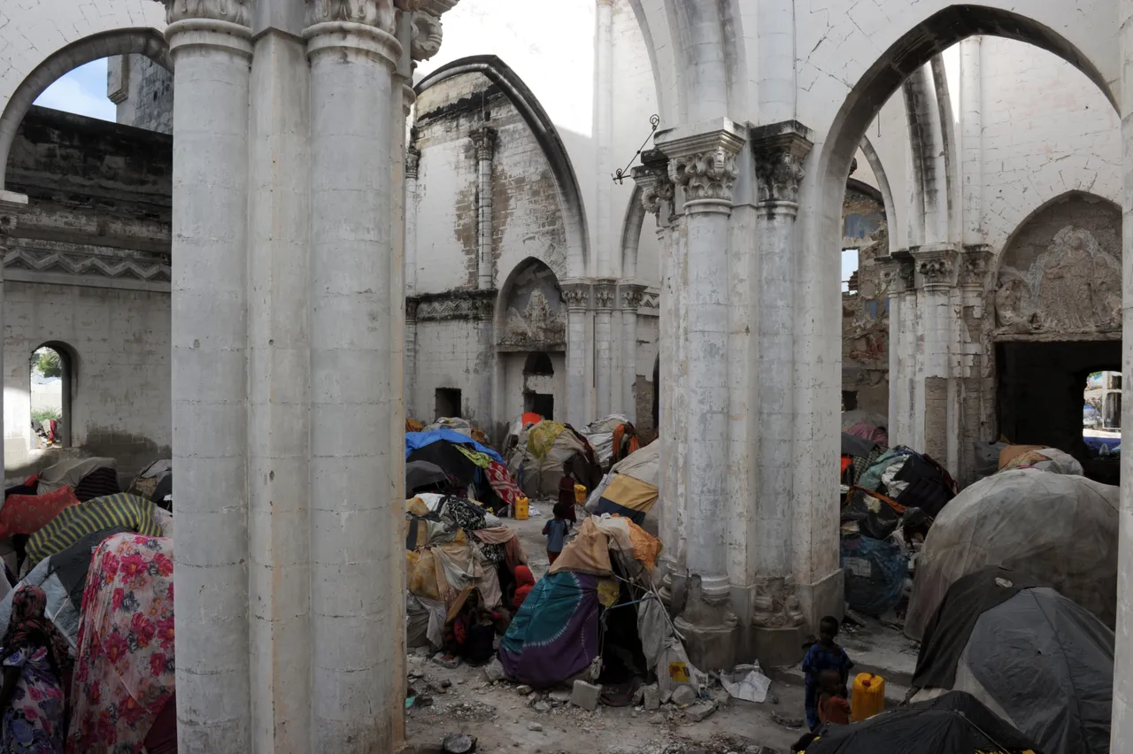 Somali children stand near makeshift shelters set up in the remains of a Roman Catholic Cathedral in Modadishu, Somalia on August 18, 2011. (Photo credit ROBERTO SCHMIDT/AFP via Getty Images)