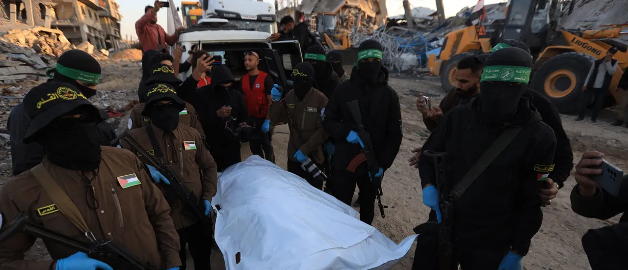 Islamic Jihad and Hamas militants stand next to a white body bag believed to contain the remains of an Israeli hostage in the town of Beit Lahia in the northern Gaza Strip on December 3, 2025.
