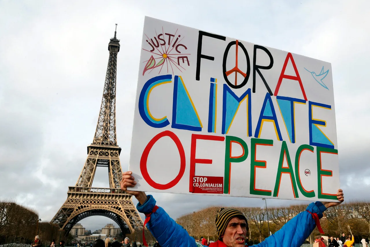 Protestor holds sign near the Eiffel Tower in Paris on December 12, 2015 on the sidelines of the COP21, the UN conference on global warming. (Photo by FRANCOIS GUILLOT/AFP via Getty Images)