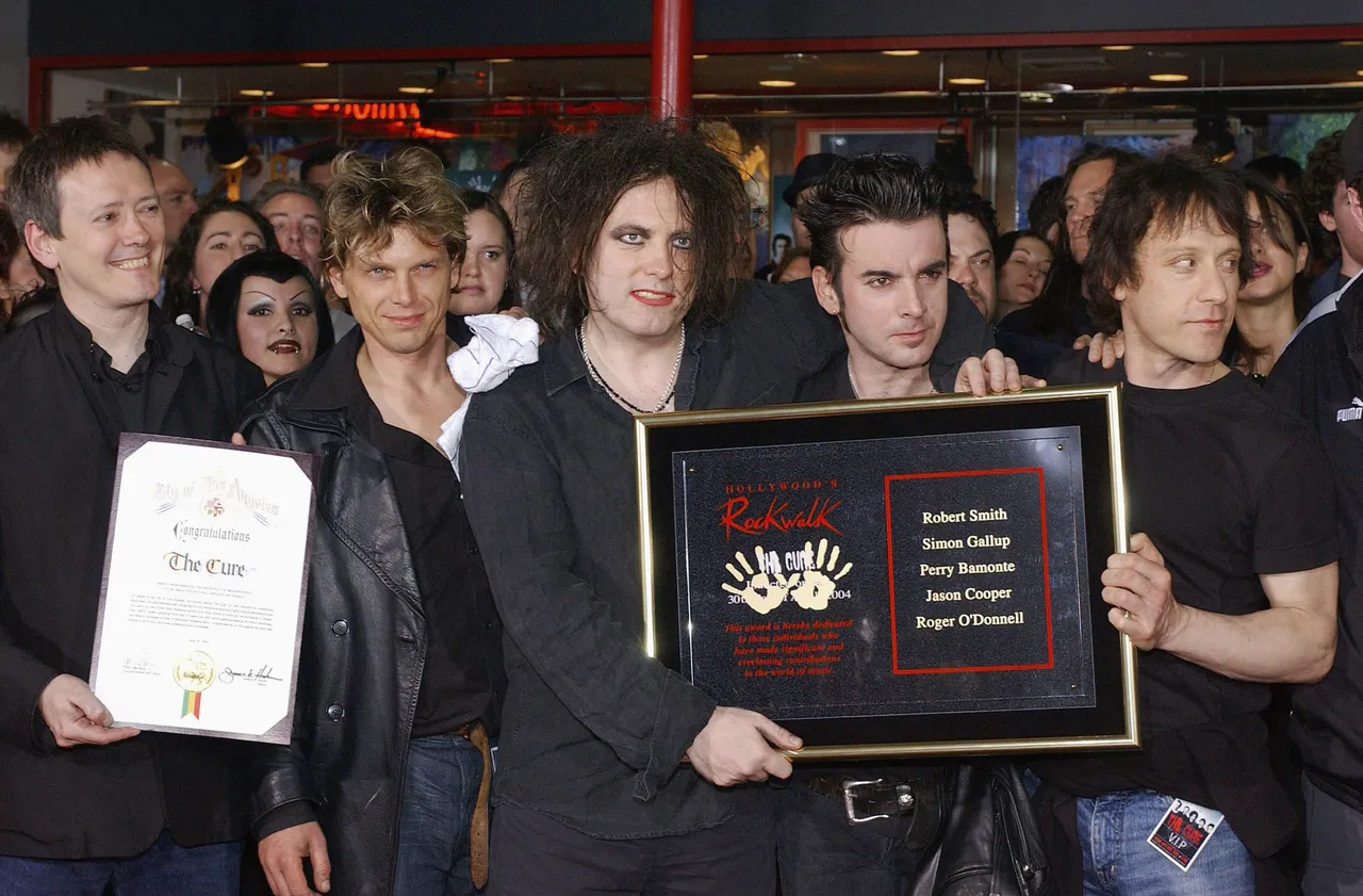 HOLLYWOOD - APRIL 30: Members of the English rock band The Cure (from left): Roger O'Donnell, Jason Cooper, Robert Smith, Simon Gallup and Perry Bamonte pose during their induction into the Rock Walk at the Guitar Center on April 30, 2004 in Hollywood, California. (Photo by Vince Bucci/Getty Images)