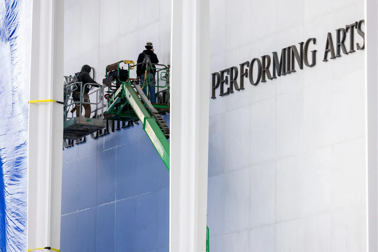 A crew can be seen working on the wall of The John F. Kennedy Memorial Center for the Performing Arts as the building is renamed in honor of US President Donald Trump on December 19, 2025, in Washington, DC. The US capital's renowned John F. Kennedy arts center is to be renamed the "Trump-Kennedy Center" after President Donald Trump, the White House announced on December 18, 2025. Press Secretary Karoline Leavitt said the center's board -- which Trump purged of Democrats earlier this year -- voted for the change because of the Republican's "unbelievable work" in overhauling the famed venue. (Photo by Jim WATSON / AFP via Getty Images)