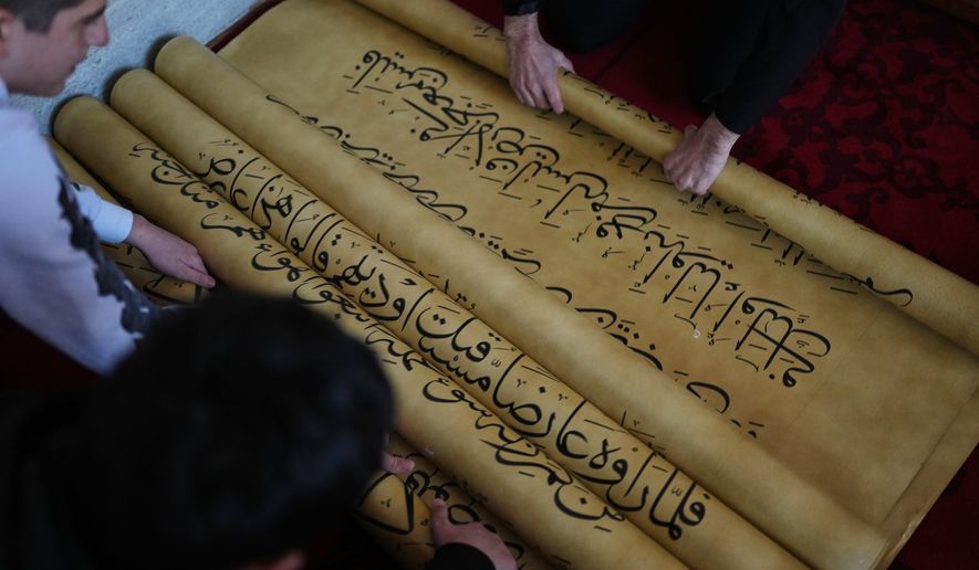 Islamic school students unroll scrolls of a massive handwritten manuscript of the Quran, Islam's holy book, by Iraqi calligrapher Ali Zaman, at the Mihrimah sultan mosque, in Istanbul, Turkey, Wednesday, Jan. 14, 2026. (AP Photo/Francisco Seco)