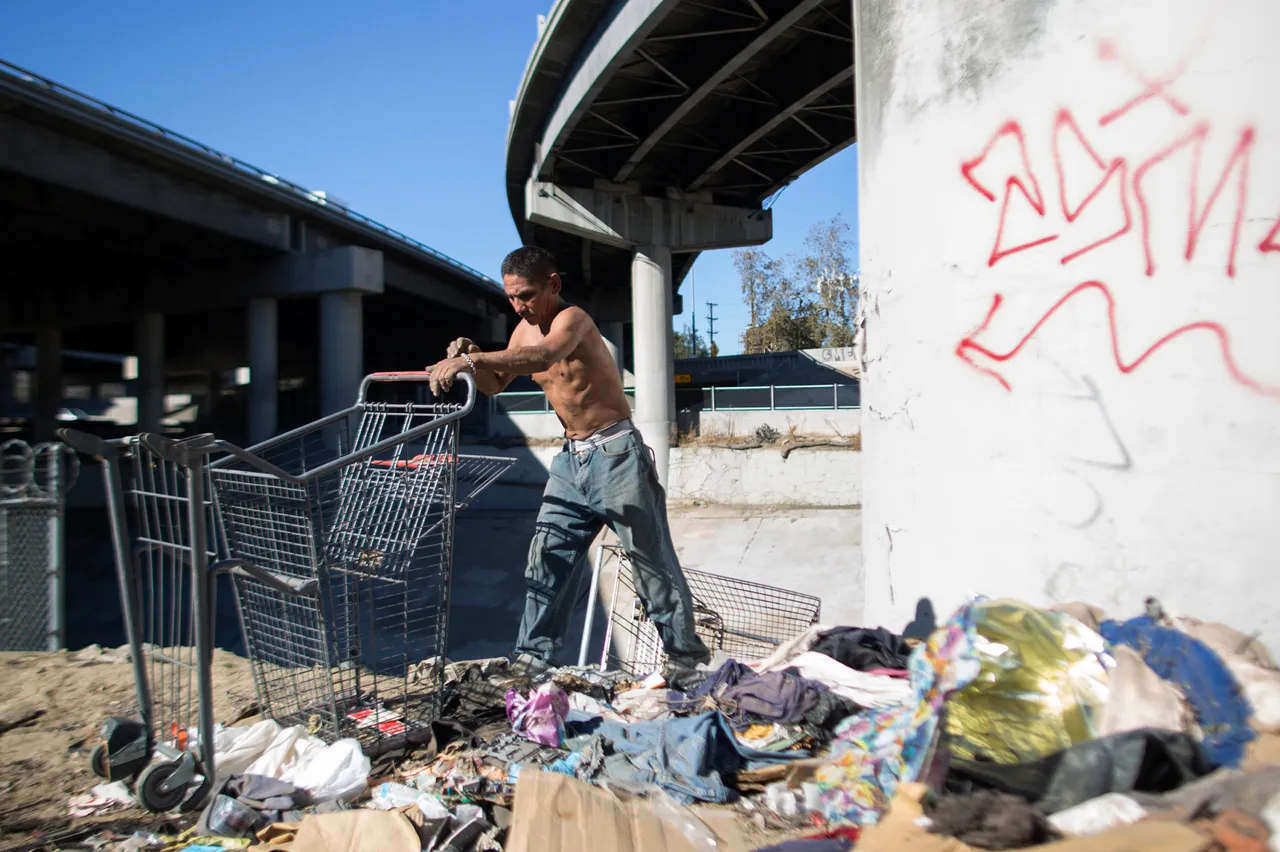 Rocky cleans up the encampment of homeless friends who are faced with imminent eviction while they are away, near the concreted channel of the Arroyo Seco Creek on November 20, 2015. (Photo by David McNew/Getty Images)