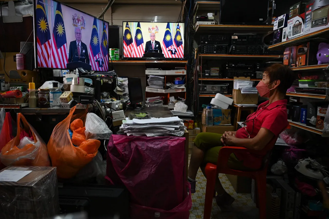 A woman watches television on display at a shop as Malaysian Prime Minister Ismail Sabri Yaakob announces the dissolution of parliament as he addresses the nation during a live telecast, in Bentong, Malaysia's Pahang state, on October 10, 2022. Image not from story. (Photo by MOHD RASFAN/AFP via Getty Images)