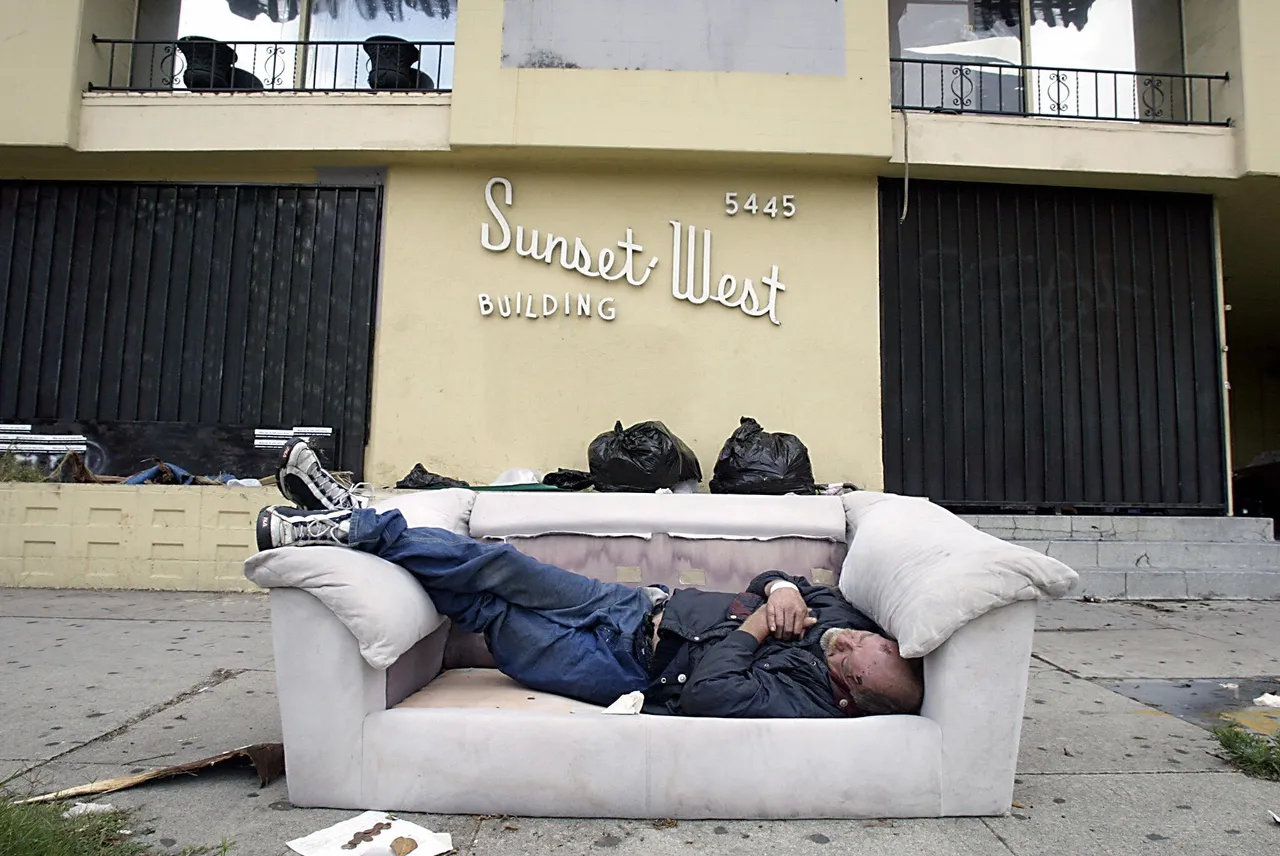 A homeless man sleeps in a couch on the sidewalk of Sunset Boulevard in Hollywood 11 June 2003. (HECTOR MATA/AFP via Getty Images)
