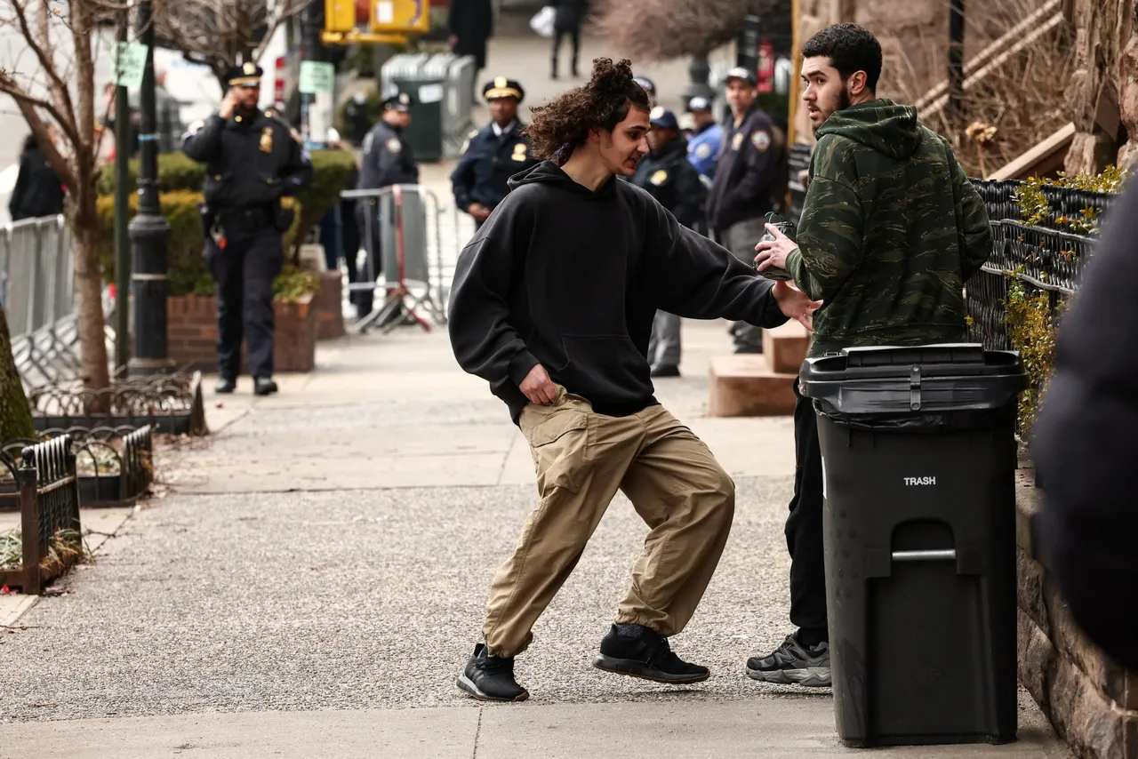 A suspect is handed a homemade explosive device by another young man before throwing it towards police during a protest organized by influencer Jake Lang against alleged "Islamification" and to ask for a "stop of public Muslim prayer" in New York, in front of Gracie Mansion, New York mayor Zohran Mamdani's official residence, in New York on March 7, 2026. (Photo by Charly Triballeau/AFP via Getty Images)