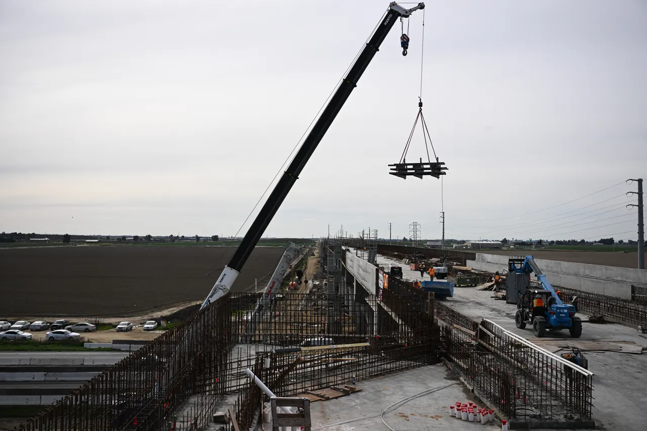 Construction workers use a crane to move equipment as they build the Hanford Viaduct over Highway 198 as part of the California High Speed Rail (CAHSR). (Photo by PATRICK T. FALLON/AFP via Getty Images)