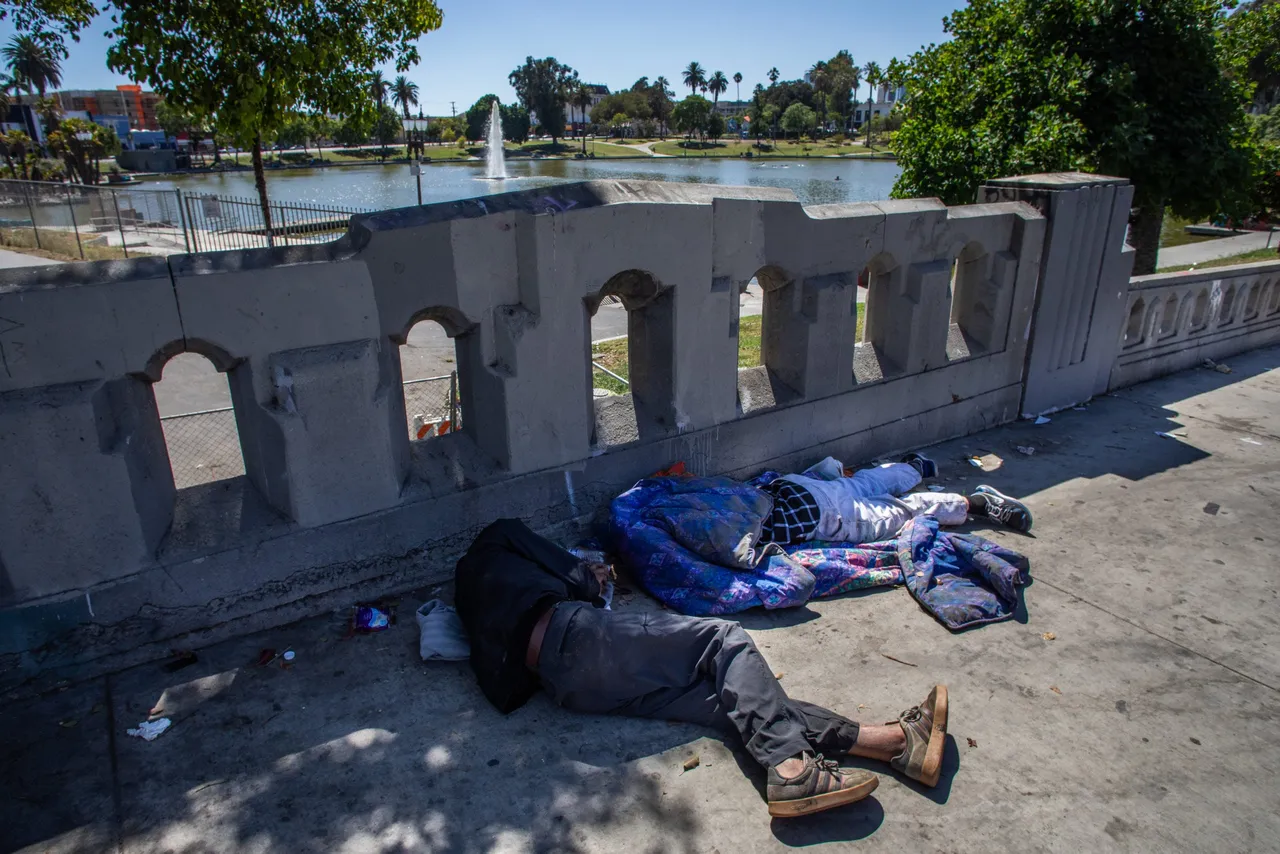 LOS ANGELES, CALIFORNIA - JULY 25: Homeless men sleep on the sidewalk at the MacArthur Park on July 25, 2025 in Los Angeles, California. (Photo by Apu Gomes/Getty Images)