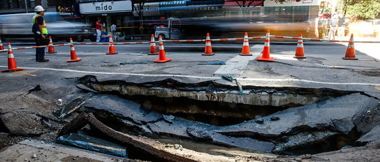 NEW YORK, NY - AUGUST 30: Traffic passes by a sinkhole caused by a water main break on Amsterdam Avenue, in the Upper West Side section of Manhatten, August 30, 2016 in New York City. Water started flowing Monday night from a broken pipe and crews continued with repairs on Tuesday morning. (Photo by Drew Angerer/Getty Images)