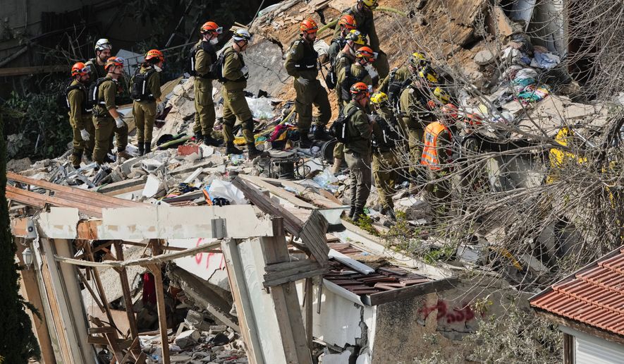 Israeli rescue teams search for missing people amid the rubble of a residential building a day after it was struck by an Iranian missile in Haifa, Israel, Monday, April 6, 2026. (AP Photo/Ariel Schalit)